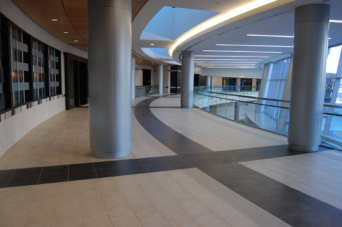 Atrium walkway at Baylor Cancer Center curving past steel columns, dark and light tile floor