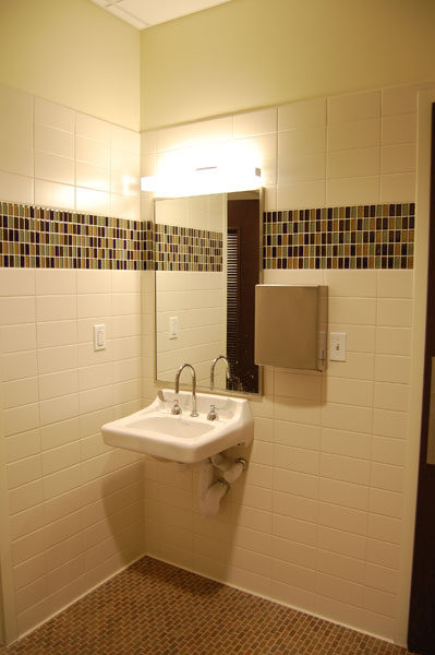 Restroom at Baylor Cancer Center with a band of mosaic tile across a light tile wall