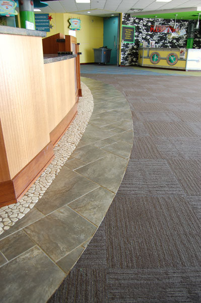 Curved stone border with pebble inlay between carpet and tile at The Hills Church