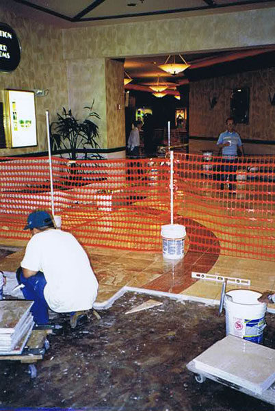 Setter kneeling on the floor at Hollywood Casino, laying a stone inlay behind temporary orange fencing