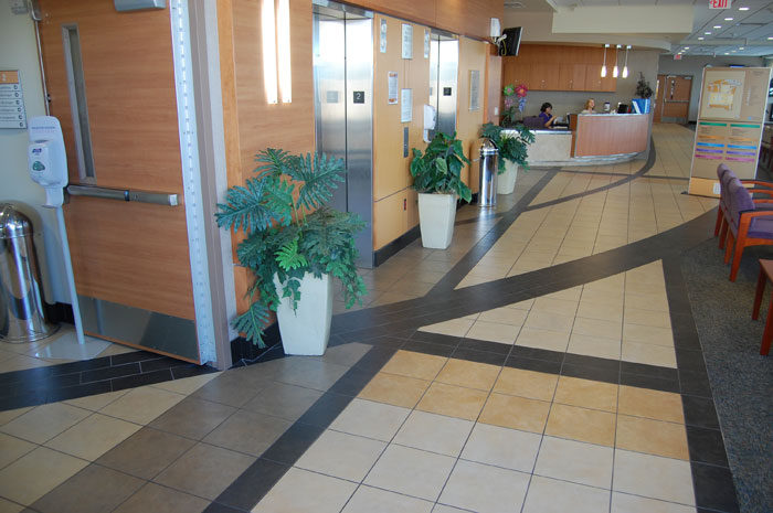 Corridor at John Peter Smith Hospital: a dark tile stripe running down a light tile floor past a reception desk