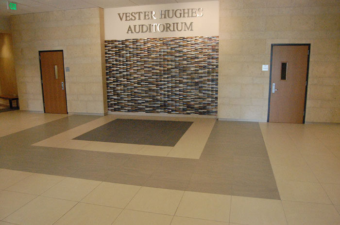 Lobby at SMU Caruth Hall: a stone feature wall and a bordered tile floor